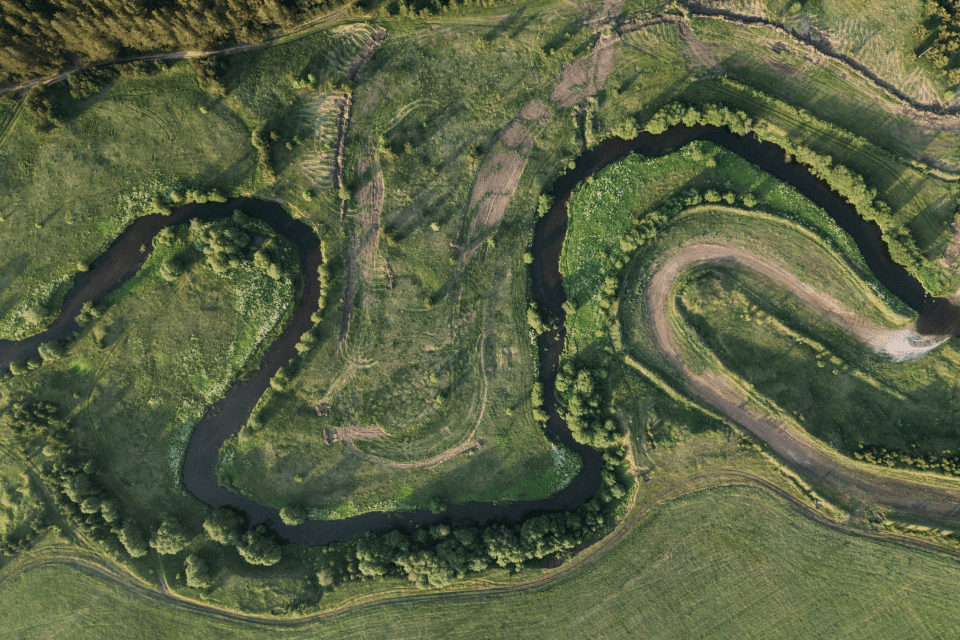 Aerial view of a winding creek flowing through a green landscape